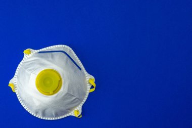 Mavi arka planda tıbbi güvenlik maskesi. Coronavirus hücresi Covid-19 virüsü önleme yolu ile korunuyor. Pandemik sağlık riski kavramı. Yüzen Çin patojeni.
