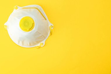 Coronavirus 2019-nCov roman koruma enfeksiyonu konsepti. Hijyenik maske veya sarı arka planda cerrahi kulak ilmeği maskesi kırpma yolu ile