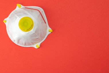 Kırmızı arka planda tıbbi güvenlik maskesi. Coronavirus hücresi Covid-19 virüsü önleme yolu ile korunuyor. Pandemik sağlık riski kavramı. Yüzen Çin patojeni.