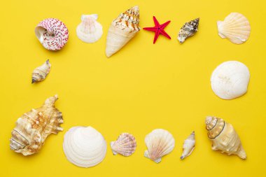 Kabuklar, sarı arka planda izole edilmiş kırmızı deniz yıldızı ve mesaj için boş alan. Üst düzey seyahat ya da tatil konsepti. Yaz dönemi. Düz yatış, üst görünüm