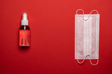 Virüs koruması. Tıbbi maske, dezenfektan jeli ve kırmızı arka planda laboratuvar eldivenleri. Coronavirus hastalığı COVID-19 salgını olabilir. Tıbbi solunum bandajı yüzü
