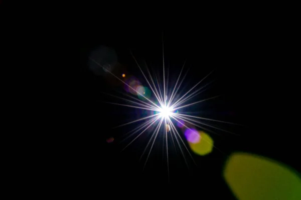 플레어 선광을 내리 세요. 태양 광선의 번쩍 임 효과 또는 별의 점 광은 검은 배경에 밝게 빛난다. 둥그스름하고 육각형인 무지개 할로. — 스톡 사진