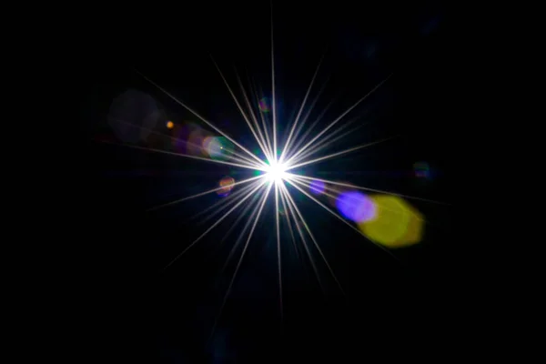 Fondo abstracto de luz solar. Rayo de efecto flash en negro. El punto de estrella o el sol brillan con luz brillante en la lente. Luces Bokeh y reflejo óptico de fugas — Foto de Stock