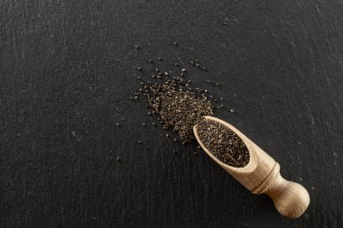 Tahta kaşıkta sağlıklı keten tohumu. Siyah gıda arka planında izole edilmiş süper yiyecekler. Vitaminli kahvaltı, diyet ve sağlıklı beslenme konsepti..