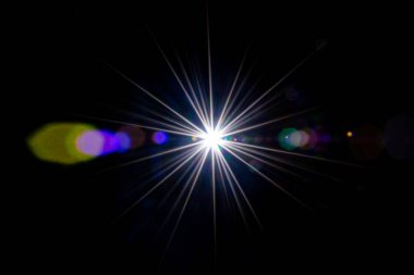 İşaret fişeği arka planı. Güneş ışığı ışığı ışığı siyaha etki ediyor. Yıldız lekesi ya da güneş objektifte parıldıyor. Parıltılar yuvarlak ve altıgen şekiller, gökkuşağı halesi