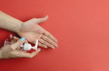 Tıbbi laboratuvar eldivenlerinde kırmızı arka planda el dezenfektanı jeli kullanmak. Pompa şişesinde mikropları ve bakterileri öldürmek için dezenfektan var. Corona Virüsü sık sık ellerini yıkayarak salgın hastalıktan korunuyor.