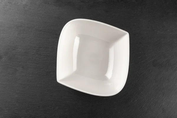 Квадратная белая пустая тарелка для ужина на темном фоне. Блюда изолированы на камне. Ресторан кухня минималистская концепция . — стоковое фото