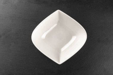 Taş üstüne beyaz tabak. Karanlıkta izole edilmiş boş bir tabak. Yemek geçmişi. Restoran mutfağı minimalist konsepti.