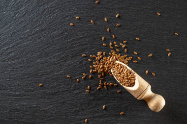 Keten tohumu, keten tohumu, organik gıda geçmişi. Kahverengi keten, ahşap kepçe içindeki keten tohumu yağ izole edilmiş koyu taş için. Omega 3 'ün vegan kaynakları ve doymamış yağlar. Sağlıklı gıda kavramı.