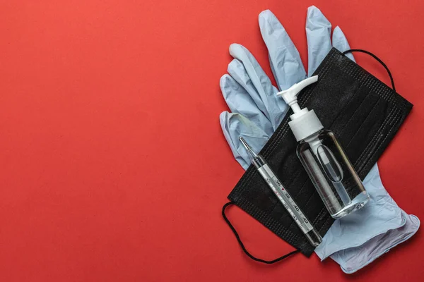 Medical equipment background. Protective masks sanitizer gel, thermometer and lab gloves on red. Coronavirus disease. 2019-nCoV. WUHAN corona virus concept. Medical protective shielding bandage