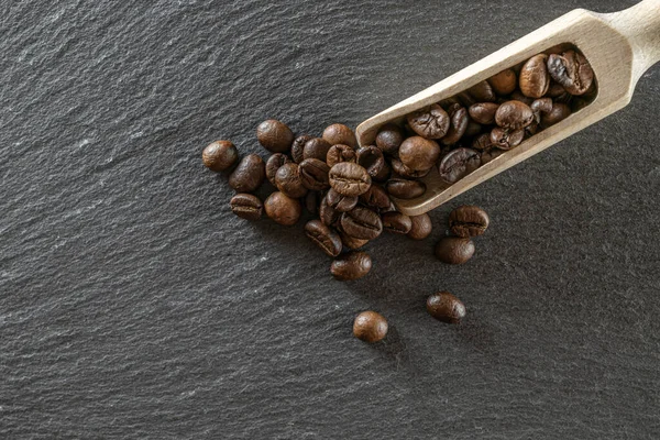 Coffee beans on black caffeine breakfast background. For cup of dark espresso food or drink. Assorted ground and instant brown roasted coffee seeds on stone. Copy space, top view.