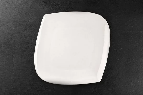 Placa de porcelana blanca en la mesa. Fondo de la cena. Vaciar redondo aislado sobre fondo de piedra. Restaurante cocina concepto minimalista . —  Fotos de Stock