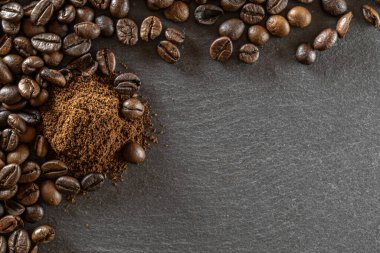 Siyah gıda arka planında koyu kafeinli espresso için fasulye. Kafede bir fincan kahve içmek için. Kahverengi kavrulmuş kahve çekirdekleri enerji kahvesi için izole edilmiş, kapuçino malzemesi. Boşluğu kopyala, üst görünüm