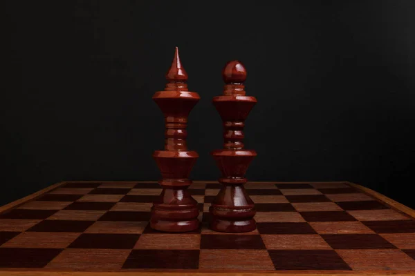 Schaken. Zwarte koning en koningin op een houten bord. De meest krachtige cijfers. — Stockfoto