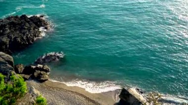 4K film drone üst görüntü görüntüsü turkuaz deniz dalgaları kumlu sahil şeridinde kırılıyor. Kumsalın derin mavi okyanus suyu ve köpüklü dalgalarla buluşmasının havadan çekimi.