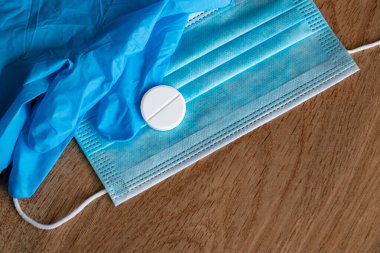 Aşı COVID-19 Coronavirüs. Plastik tıbbi maske, tek kullanımlık plastik eldivenler, beyaz bir tabletle. Coronavirus tableti. Ahşap bir arka planda Coronavirus 'un koruyucu ekipmanları. Boşluğu Kopyala.