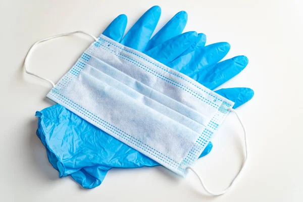 Coronavirus COVID-19 koruması. Plastik eldiven ve maske. Beyaz arka planda Coronavirus 'tan tek kullanımlık koruyucu ekipman ögeleri.