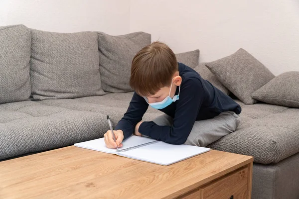Coronavirus salgını. Maskeli bir çocuk karantinaya alındı. Uzaktan eğitim ve öğrenme. Kendini izole et, ev karantinası. Dünya Krizi COVID-19. Evde uzaklık öğrenimi.