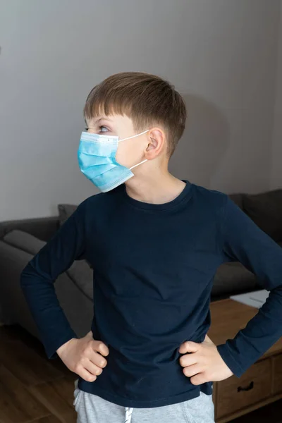 Niño con máscara médica azul en cuarentena de coronavirus en casa. Control epidémico de COVID19 y prevención adecuada de la infección. Niño en máscara casa cuarentena auto aislado —  Fotos de Stock