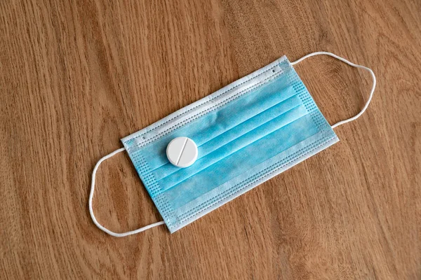 Coronavirus aşısı COVID-19. Plastik tıbbi maske ve tablet. Coronavirus tableti. Tahta bir arka planda Coronavirus 'tan alınan koruyucu ekipman parçaları.