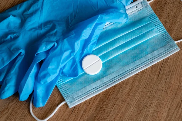 Aşı COVID-19 Coronavirüs. Plastik tıbbi maske, tek kullanımlık plastik eldivenler, beyaz bir tabletle. Coronavirus tableti. Ahşap bir arka planda koronavirüsten koruyucu ekipmanlar.