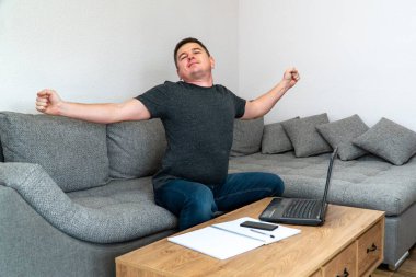 Coronavirus. Maskeli işadamı evde karantinada çalışmaktan yoruldu ve zarifçe esniyor. Koronavirüs salgınından sonra evden telgraf gönderen adam..