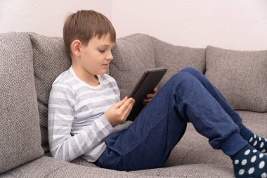 Uzaktan öğrenme çevrimiçi eğitim. Tablet 'in önünde düşünen genç bir çocuğa bakıyorum.
