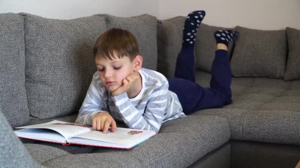 Kształcenie online na odległość. Dzieciak w izolacji szkolnej za pomocą tabletu do pracy domowej, znudzony dziecko smutna twarz leżąc głową w dół patrząc w głąb myśli, chłopiec pobyt w domu podczas covid-19 blokady w dół. — Wideo stockowe