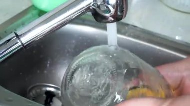 Çevre dostu yemek takımı. Plastiği durdur. Kadın elleri akan suda cam bir kavanozu yıkıyor. Çevre dostu yemek takımı.