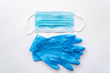 Coronavirus COVID-19 koruyucu denekler. Tek kullanımlık plastik eldivenler ve beyaz bir arka planda maske.