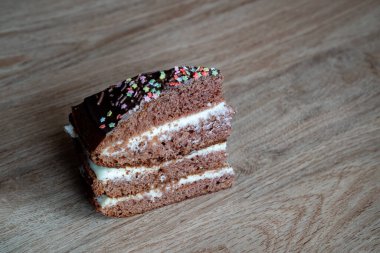 Çikolatalı kek. Tabakta bir parça kek var. Tatlı yemek. Tatlı tatlı. Ahşap arka plan. Tahta bir stantta. Kapatın. Metin yazmak için yer.