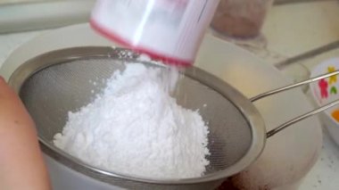 Aşçı toz şekeri bir metal elek vasıtasıyla bir kaseye eledi. Evde pişir.