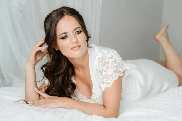 Yatakta gelin. Gayri resmi iç çamaşırı giyen güzel bir genç kadın. Yatakta zarif bir kadının moda portresi.
