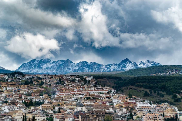 Snow clouds over a village in the snowy mountains of the Sierra Nevada of Spain. Beautiful Winter View Over a Snowy Mountain