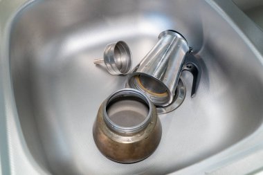 Parçalanmış kahve makinesi lavaboda. Ocakta kahve makinesi var. İtalyan espresso kahve makinesi ya da lavaboda parçalanmış Moka demliği..