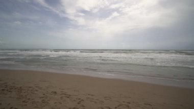 Deniz sörfünün geniş açılı panoramik görüntüsü. Kumlu Akdeniz Sahili 'nin bulutlu sabahı. Guardamar del Segura 'daki Akdeniz kıyıları, Torrevieja, Alicante. Ses ile video görüntüleri