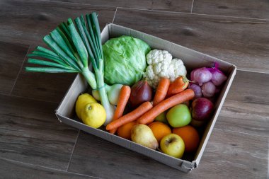Kahverengi ahşap arka planda karton kutuda taze sebzeler. Vejetaryenlik için bir kutu