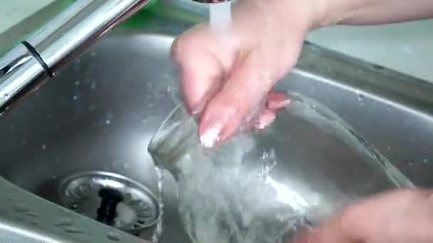 Las manos femeninas lavan el frasco de cristal en el agua corriente. Vidrio en lugar de plástico. utensilios de cocina ecológicos — Vídeo de stock