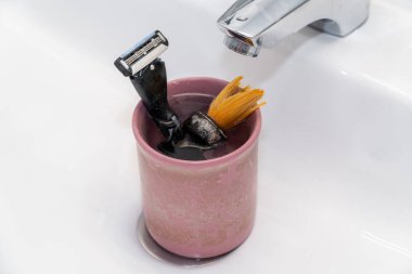 Male old used shaving kit in the wash basin. Shaving accessories in a glass clipart