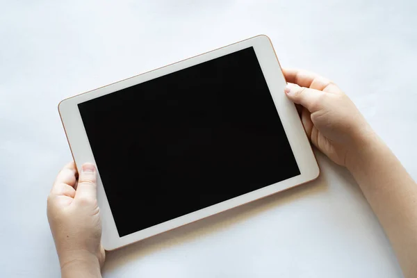 Bir çocuk elinde tablet bir telefonla beyaz bir arkaplan tutuyor..