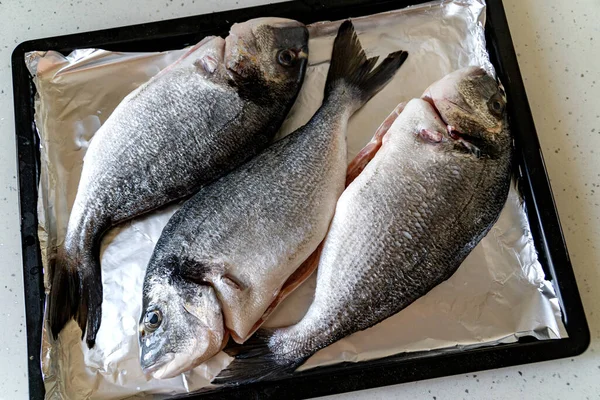 Raw Dorada Fish på en bakplåt. Matlagning av fisk hemma — Stockfoto