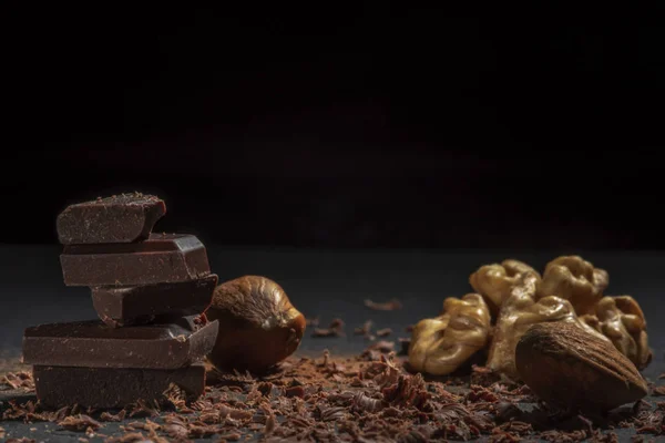 El chocolate negro en las nueces sobre la piedra. Fondo oscuro . — Foto de Stock