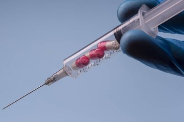 Syringe with pills on a blue background. Pills in a syringe.