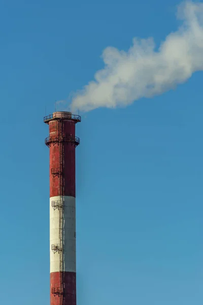 Vertical image of an industrial chimney with white smoke causing air pollution.