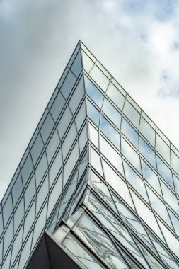 Modern mimarinin soyut bir parçası, cam ve betondan bir duvar. Bulutlu gökyüzü.