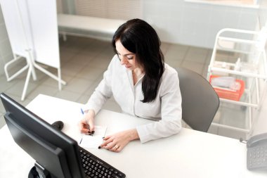 Laptop bilgisayarında çalışan kadın doktorlar, hastane veya klinikteki kayıt bilgileriyle reçeteli not defterleri, sağlık hizmetleri ve tıbbi konsept