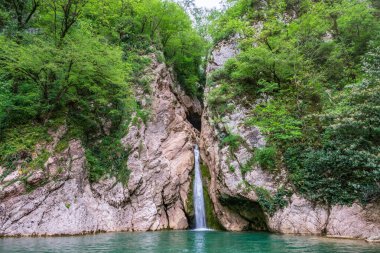 Yüksek bir şelale uçurumdan açık bir göle düşüyor.