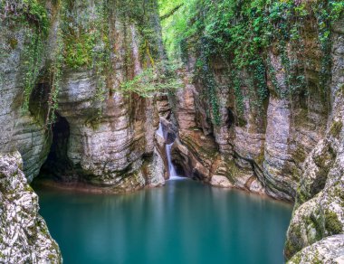 Dağ nehri ve şelale. Taştan bir vadide berrak turkuaz suyu..
