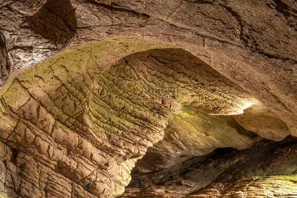 Vista interior de la antigua cueva con paredes de piedra con iluminación adicional. Textura de un muro de piedra en una cueva . —  Fotos de Stock