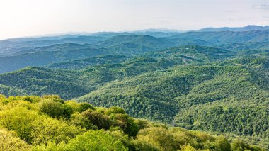 Gün batımında sis içinde dağların katmanları. Dağlarda güzel gün batımı. Ovalarda köyler ve sis ile tepelik bir vadide güzel gün batımı.